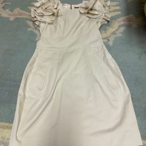 A beige dress with flower ruffles on the sleeve